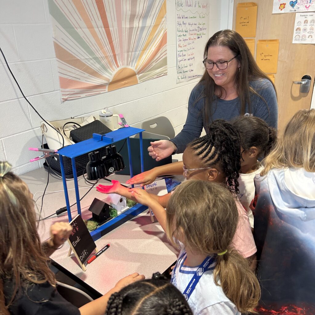Photo of students experimenting with different colored materials under a heat lamp